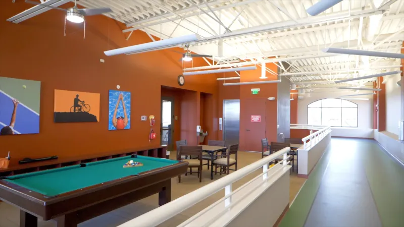 In the billiard room, a pool table takes center stage, surrounded by brightly painted walls adorned with colorful artwork and comfortable seating areas.
