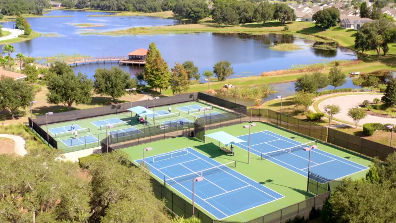 Scenic view of Del Webb Orlando tennis and pickleball courts, set against the backdrop of a serene lake.