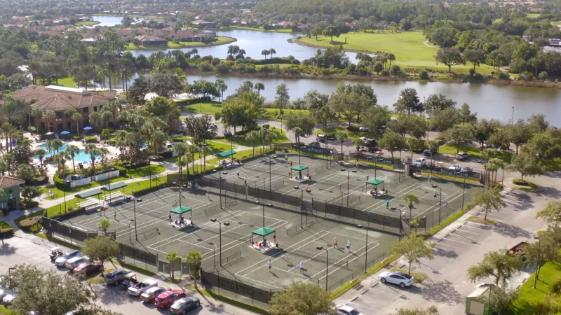 Overhead view of the Pelican Preserve tennis courts and a pool by a lake.