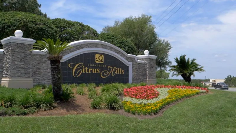 The Villages of Citrus Hills monument sign surrounded by red and yellow flowers.
