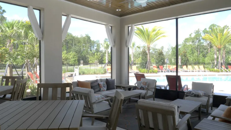 Cabana area with tables, chairs and couches next to pool.