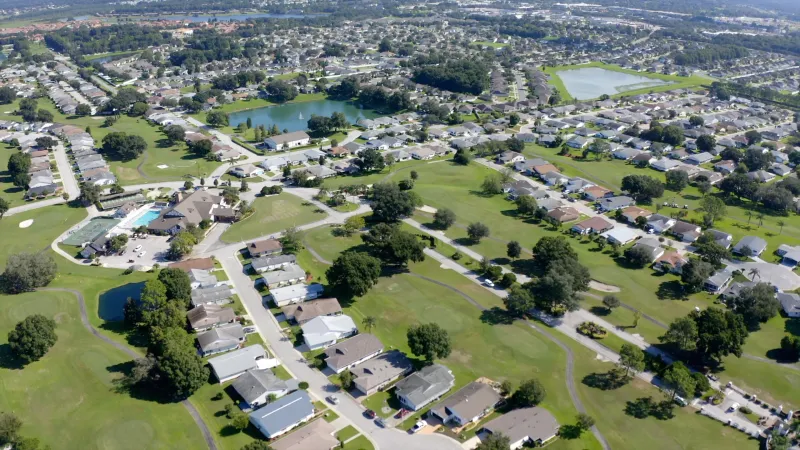 Main road in Highland Fairways with homes on either side and pond in background.