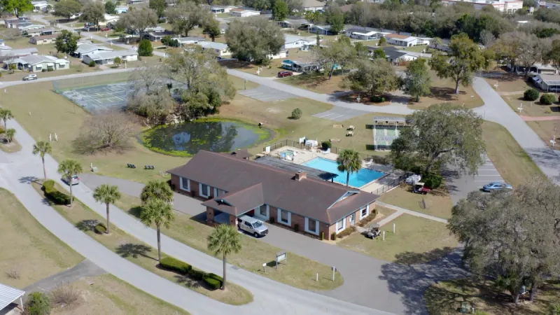 Aerial view of clubhouse, pool area, and sports courts.