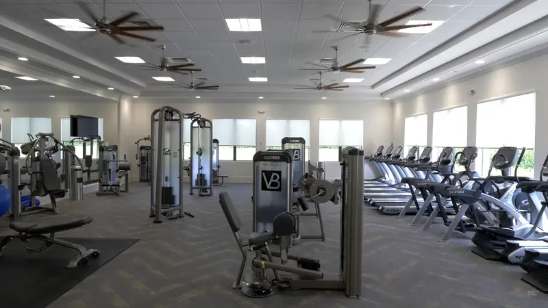 A well-equipped gym with various exercise machines and large windows.