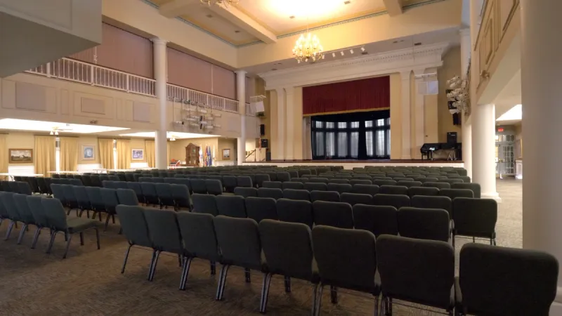A spacious Plantation at Leesburg meeting room with several rows of chairs and a stage at the front for performances or speakers.