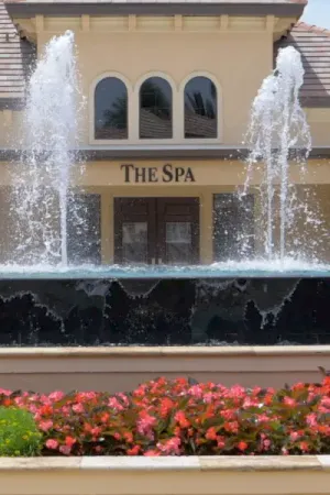 Red flowers in front of a fountain with water features at entrance of The Spa.