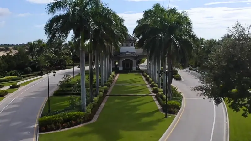 Wide view of the gated entrance to Valencia Cove lined with palm trees.