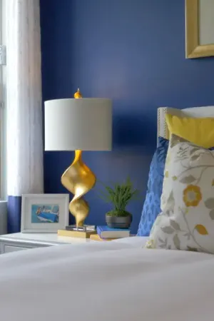 A nightstand with a frame and lamp next to a bed in the Palms at Serenoa model.