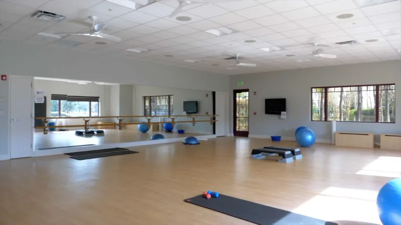 Yoga studio with yoga mats, exercise balls and a wall length mirror.