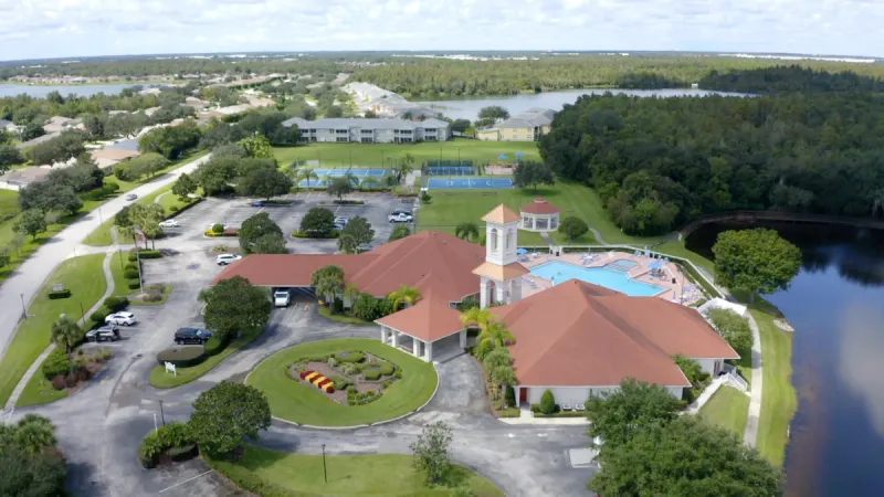 Clubhouse, pool, and sports courts surrounded by lush greenery.