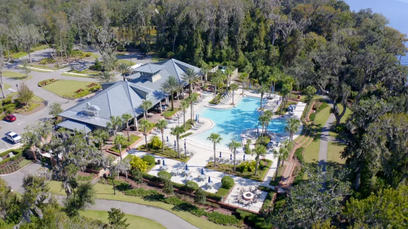 Aerial view of the WaterSong at RiverTown clubhouse and spacious pool nestled among tall trees.