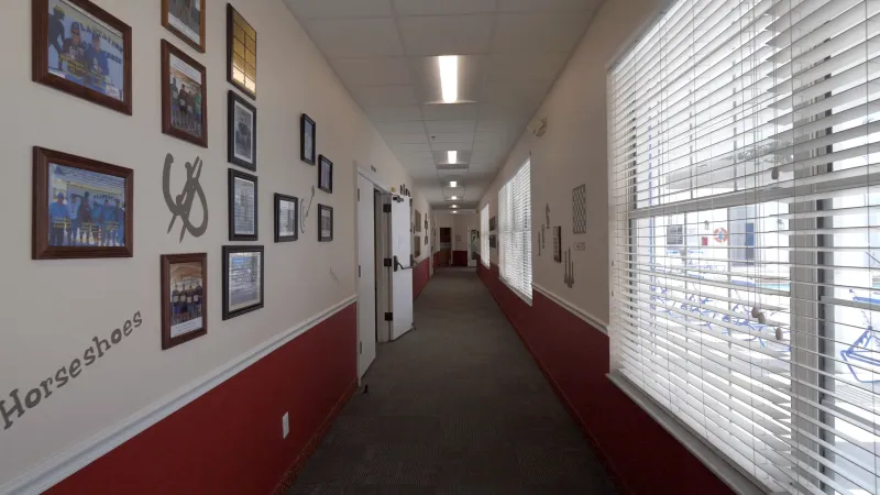 Vibrant hallway with half-walls painted a deep red, framed photos and artwork are displayed on the upper portion of the walls.