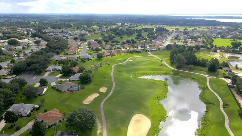 Aerial view of a sprawling golf course, highlighted by a captivating water feature and meandering cart paths.