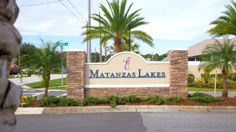 A monument sign at the entrance of the Matanzas Lakes neighborhood, displaying the name of the community with trees and landscaping surrounding.