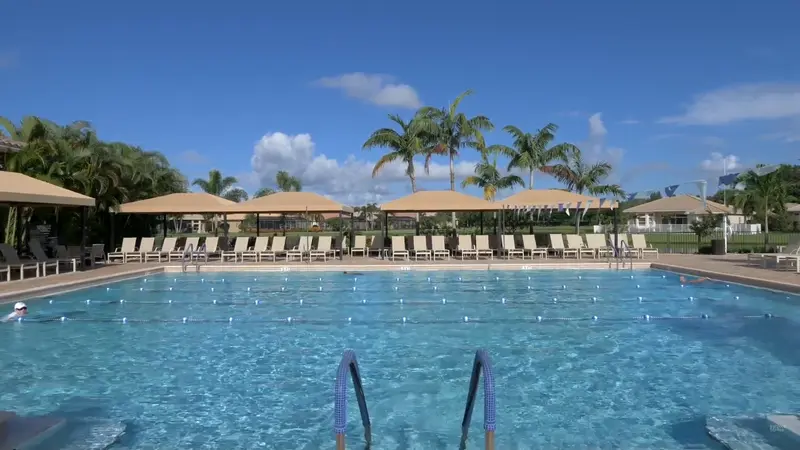 Lap pool at Valencia Cove with shaded lounge areas and palm trees.