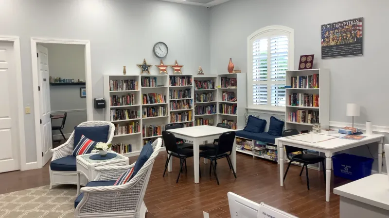 Library with a plethora of books, reading armchairs, and tables with chairs.