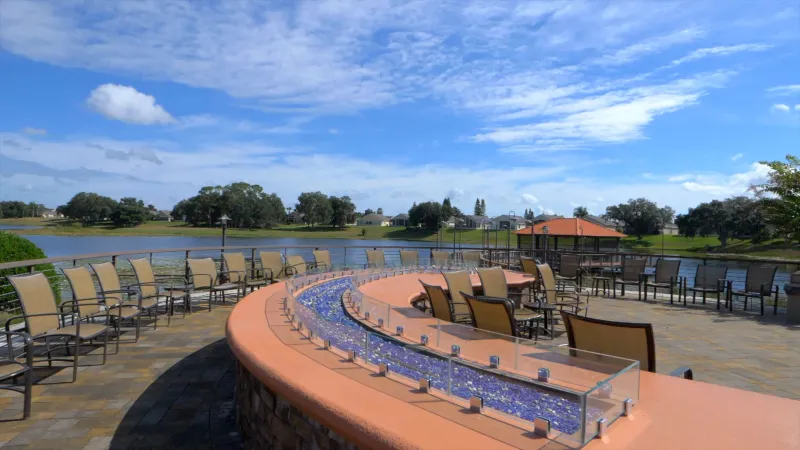 A large fire pit area with comfortable chairs arranged around it, complemented by a charming gazebo, all set against the backdrop of a tranquil lake.