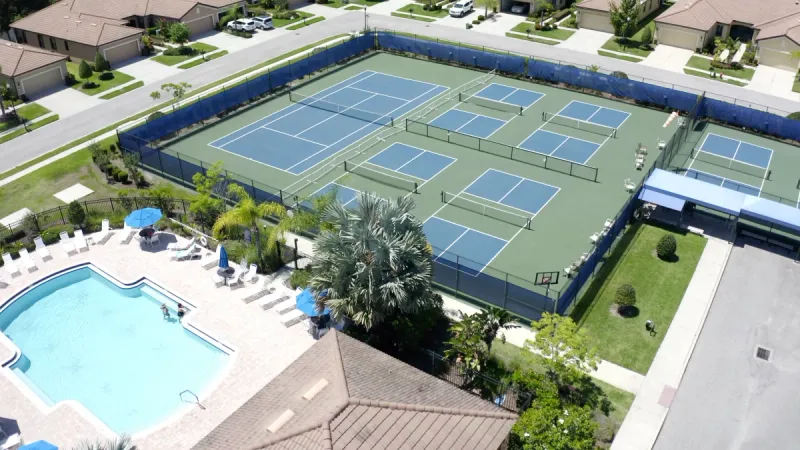 Del Webb Southshore Falls community pool area with inviting lounge spaces, complemented by adjacent tennis and pickleball courts.
