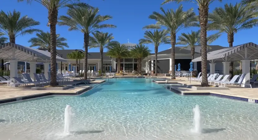  A resort-style swimming pool flanked by towering palm trees and lounge chairs under a bright blue sky at Del Webb Nocatee.