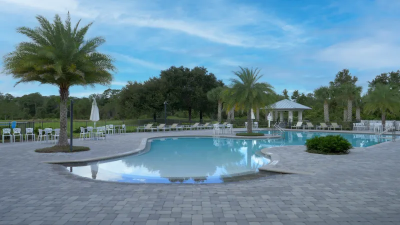 The tranquil Lakes at Harmony outdoor pool area with a gazebo, surrounded by palm trees and lounge chairs.