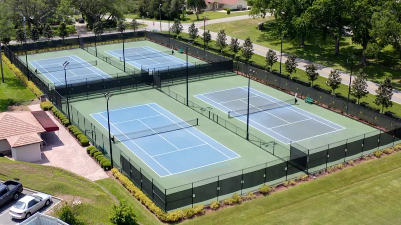 Four fenced sports courts surrounded by immaculate landscaping.