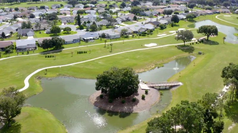 Picturesque pond set along golf fairway with houses in the background.