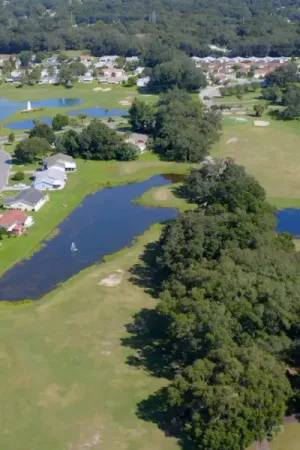 Aerial view of the golf course and homes surrounded by water features and lush greenery.