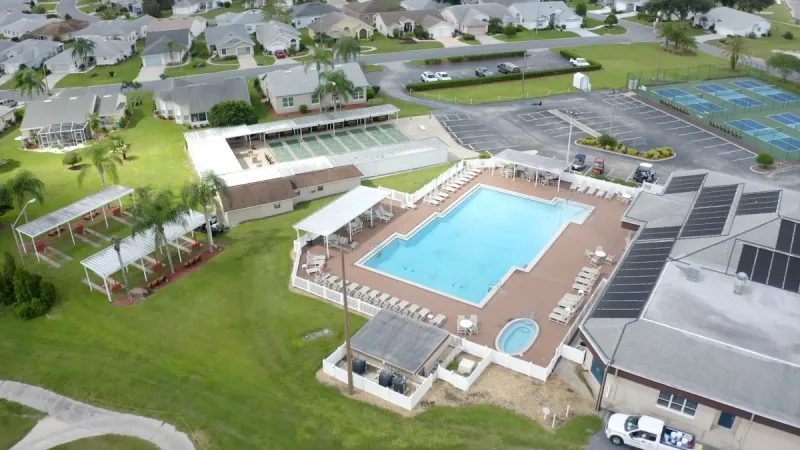Sparkling blue book and large clubhouse surrounded by sports courts.