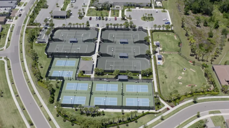 A cluster of pickleball and tennis courts, accompanied by a large dog park.