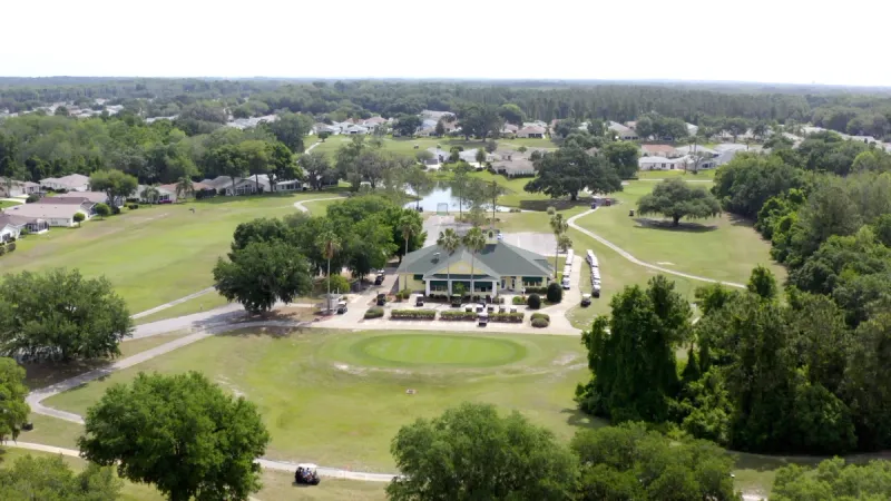 Aerial view of the clubhouse surrounded by the fairway and homes.