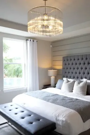 A beautifully furnished bedroom featuring a king bed and a sparkling chandelier, creating an elegant and cozy ambiance