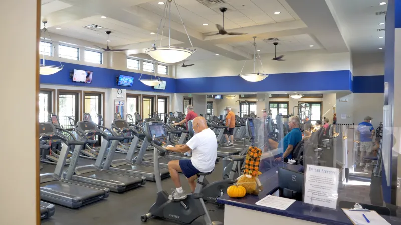 Residents staying active in the well-equipped gym with cardio machines and TVs.