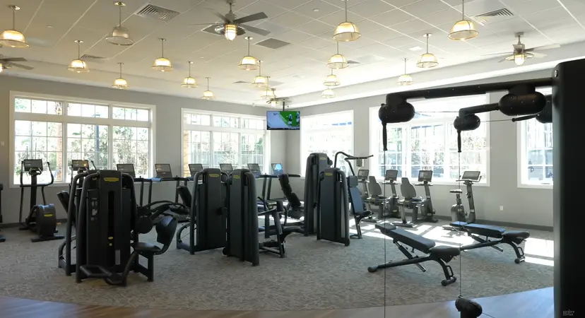 A state-of-the-art gym with various exercise machines, bright lighting, and large windows that overlook the surroundings.