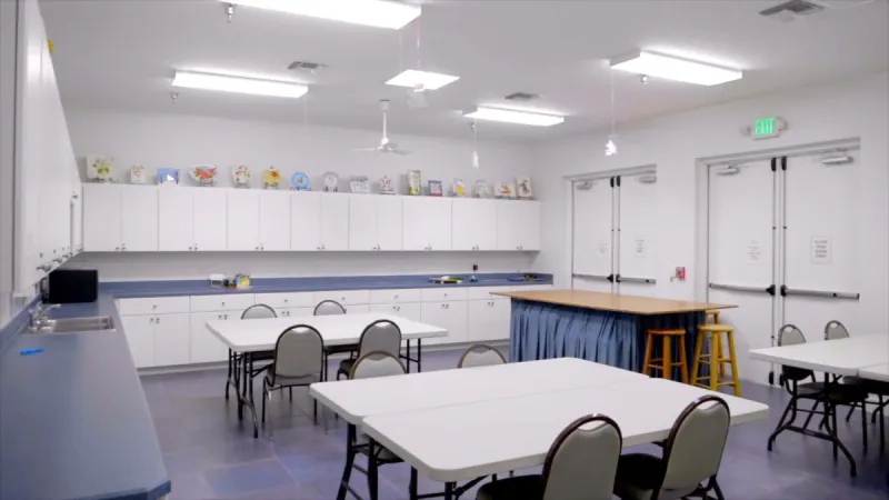 Well lit arts and craft room with work tables and seating.
