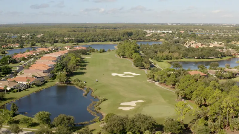 Overlooking a golf course at Pelican Preserve with sand bunkers and water hazards amid homes.