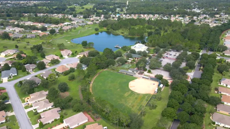 Softball field adjacent to a serene lake, framed by charming homes.