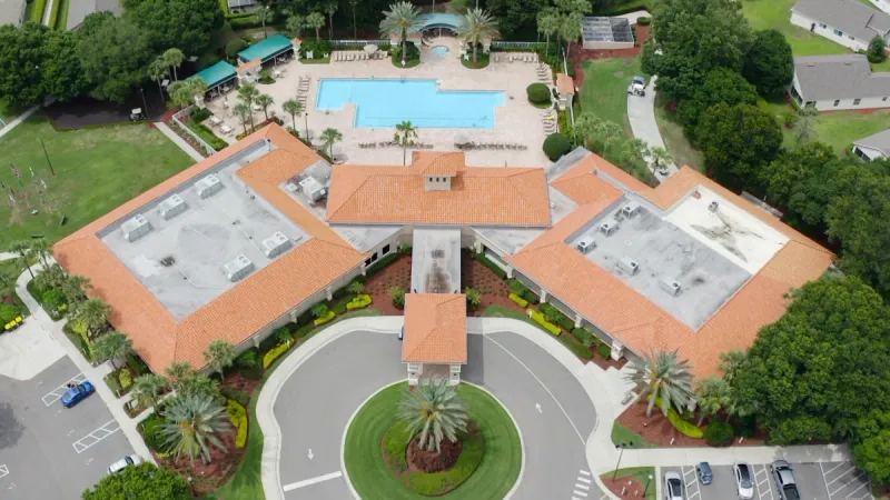 Birds eye view of the Kings Ridge clubhouse with a large outdoor pool, surrounded by palm trees.