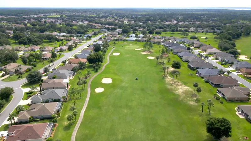 Golf fairway framed by well-manicured greens, flanked by homes on either side.