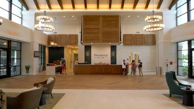 The lobby of the Hammock Club featuring a spacious interior with modern decor, a reception desk and residents mingling.