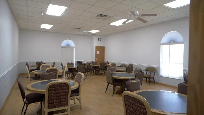 A spacious community room at Spruce Creek South with multiple round tables and chairs.