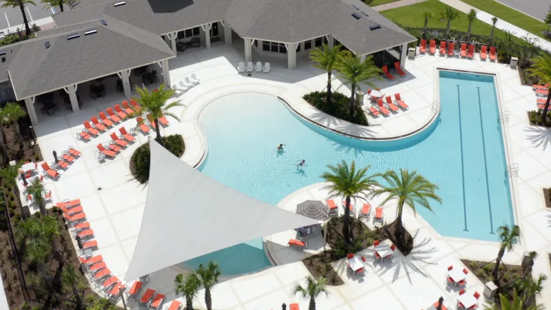 Palms at Serenoa pool area with orange lounge chairs and sunshades.