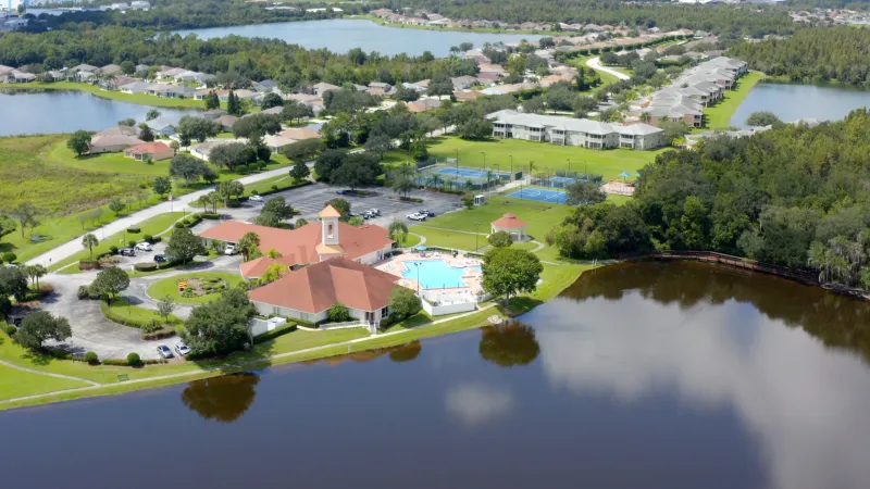 Clubhouse and amenities on lake surrounded by green spaces.