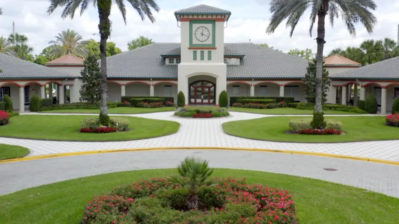 Large clubhouse with clocktower in the center, arched walkways and impecable landscaping. 