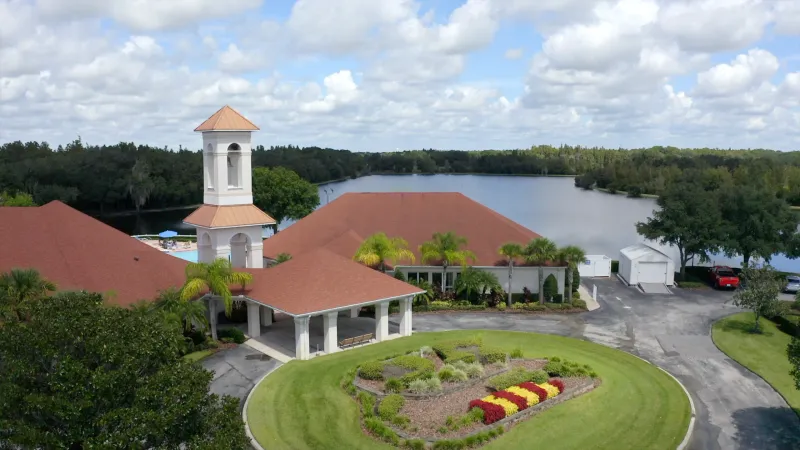 Clubhouse surrounded by lake and trees.