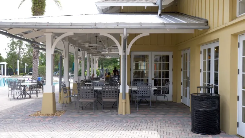 A patio area with tables and chairs under an awning.