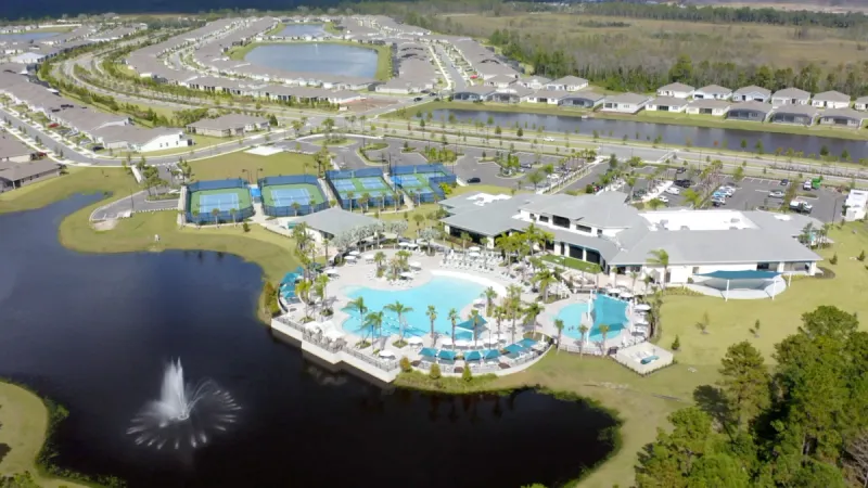 An aerial view of Del Webb Sunbridge showcasing the clubhouse, swimming pool, tennis courts and residential areas.