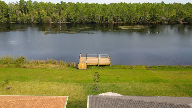 A small dock extending into the water behind homes.