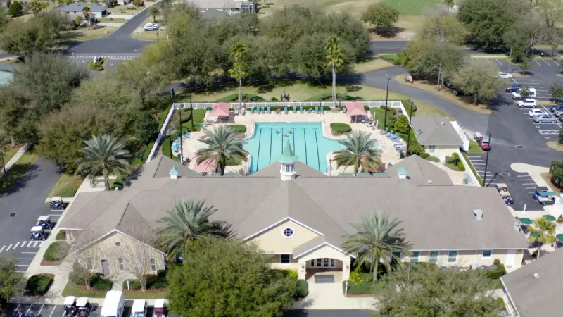 An aerial view of the SummerGlen clubhouse surrounded by lush foliage and a pool visible in the background.