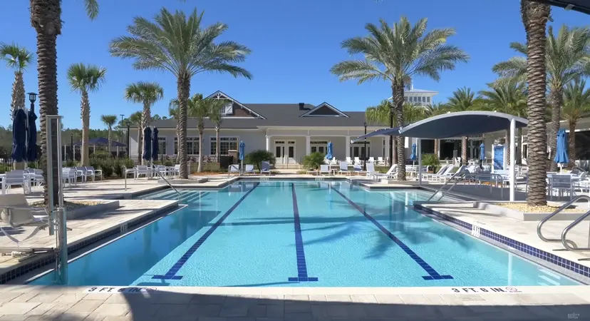 Crisp blue lap lanes in a serene outdoor pool setting, surrounded by palm trees and shaded loungers at Del Webb Nocatee.