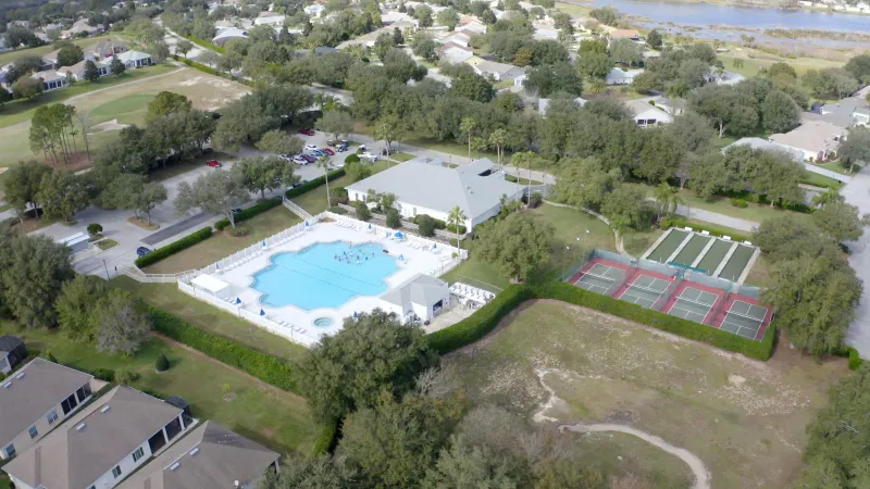 An aerial photo showcasing the pool area, as well as adjacent sports courts for shuffleboard, pickleball, and other activities.